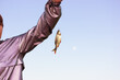 Fisherwoman holding in hand and showing a river fish caught on hook against blue sky. Sports, hobbies, fishing, angling, activities wallpaper with room for text. Freshwater Scardinius erythrophthalmus