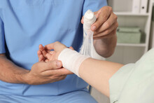 Doctor Applying Bandage Onto Patient's Wrist In Hospital, Closeup