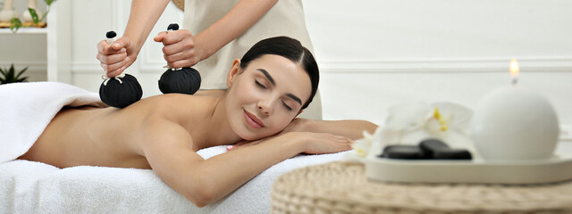 Sticker - Young woman receiving herbal bag massage in spa salon. Banner design