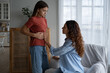 © DimaBerlin - Worried concerned mother parent examining child stomach belly at home, teen girl daughter complaining of tummy pain, kid suffering from stomachache. Menstrual cramps dysmenorrhea in teens