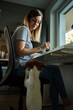 © Lazy_Bear - Woman sitting at desk table near window and looking on her dog. Remote work at home with pet