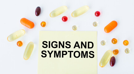 Wall Mural - text SIGNS AND SYMPTOMS on a yellow card on a white background next to scattered tablets, business concept