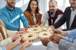 © Studio Romantic - Young business people stacking wooden gears cog in office closeup, successful cooperation, collaboration and unity concept. Focus on gears, corporate system leading to progress of company