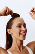 © SHOTPRIME STUDIO - A woman with long brown hair stands back and takes care of her hair after washing and combing her hair with a wooden comb. Healthy hair without hair loss