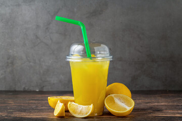 Wall Mural - Lemonade in a take away glass with cut lemon next to it on wooden table