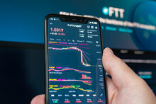 Man holding phone with FTX logo. Global fall of cryptocurrency graph - FTT token fell down on the chart crypto exchanges on app screen. FTX exchange bankruptcy and the collapse depreciation of token.