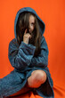© RomanR - Portrait of a pretty girl in a dressing gown posing isolated on an orange background.