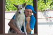 Nice outdoor portrait of Caucasian mature man and his cute young white  dog standing on summer veranda