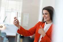 Happy Businesswoman Showing Thumbs Up On Video Call Having Through Smart Phone In Office