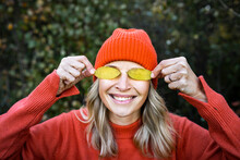 Smiling Mature Woman Covering Eyes With Autumn Leaves