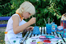 Little Girl Painting Flower Pots In Garden