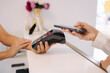 © Aleksandr - Female customer pay for procedures in beauty studio. Close-up of woman pay using phone and put to terminal. Cashier hand holding credit card reader machine while client holding phone for NFC payment