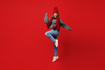 Wall Mural - Full body young excited woman wear grey sweater scarf hat jump high do winner gesture isolated on plain red background studio portrait Healthy lifestyle ill sick disease treatment cold season concept