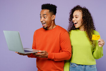 Wall Mural - Young couple two friend family man woman of African American ethnicity wear casual clothes together use laptop pc computer credit bank card shopping online isolated on plain light purple background.