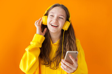 Wall Mural - teenager girl has fun indoor, listens pleasant melody in headphones,