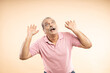 © GAJENDRRA BHATI  - Senior indian man scared with his arms up like something falling from above gesture isolated over beige background.