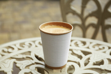 Paper cup of coffee on table outdoors. Takeaway drink