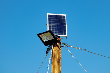 Canvas Print - Lantern and solar panel on a wooden pole close-up on a sunny day against the blue sky