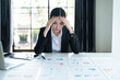 © Jirapong - A portrait of a beautiful Asian female employee showing a stressed face while using  financial documents on her desk