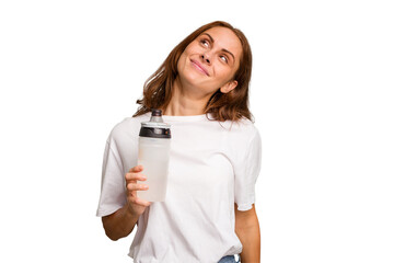 Young caucasian sport woman holding a bottle of water isolated dreaming of achieving goals and purposes