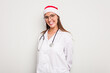 © Asier - Young caucasian doctor woman wearing a santa hat isolated on white background