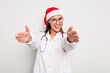 © Asier - Young caucasian doctor woman wearing a santa hat isolated on white background