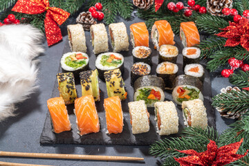 Wall Mural - Sushi set for Christmas New Year party, winter holiday food delivery menu mockup. Sushi set on slate board, with Xmas decoration copy space