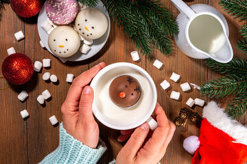 Wall Mural - Making winter hot drink, preparation funny Christmas characters with hot chocolate bomb. Homemade hot chocolate cocoa balls made with Christmas snowman, reindeer, snowflake decor