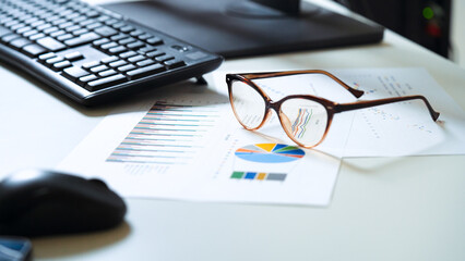 Office workplace desk. Business reports with graphics. Financial spreadshets left on the desk after a tiring day's work. Work hard.