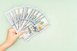 © Iana Alter - Man holds US dollar bills in his hand on green background. Copy space