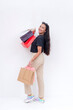 An carefree asian woman holding shopping bags on both hands after going on a shopping spree. Isolated on a white background. Retail and sale concepts.
