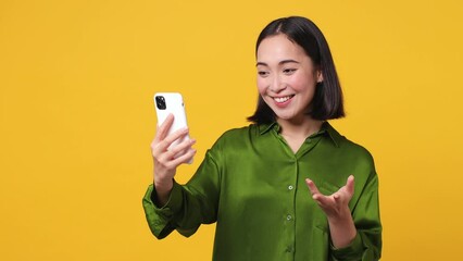 Wall Mural - Young woman she wear green shirt get video call hold use mobile cell phone doing selfie conducting pleasant conversation greet with hand isolated on plain yellow color wall background studio portrait