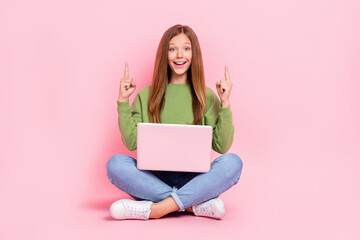 Poster - Full length photo of cute excited school girl dressed sweatshirt pointing empty space working modern device isolated pink color background