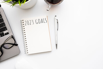 Blank notebook with pen are on top of white office desk table with laptop computer and supplies. Top view with copy space, flat lay.