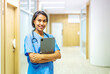 © TeTe Song - Portrait of smiling asian nurse or female doctor health worker wearing blue uniform holding digital tablet while posing on modern hallway clinic. healthcare workers