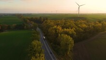 Cargo Truck With Full Of Goods Trailer Driving On Highway On Wind Turbines Background And Forest With Yellow Trees In Autumn. Business Logistic Import And Export Freight Transportation