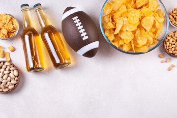 Beer in bottle and snack on concrete table with rugby ball, game night food