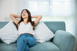 © sorapop - Asian young woman enjoying free time relaxing put arm hand back behind head on sofa in living room at home, Happy female feeling relax comfort after homework