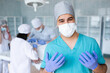 © andrey_orlov - Female surgeon with surgical mask at operating room. Young man doctor intern in surgical uniform.