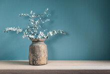 Rustic Vase With Dry Eucalyptus Leaves On Wooden Table Against Blue Green Wall. Home Decor.