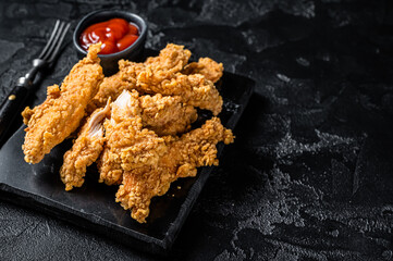 Wall Mural - Breaded chicken strips  Fingers with  Ketchup. Black background. Top view. Copy space