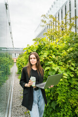 Wall Mural - Smart work concept, possibility to relocate activities. Young woman on modern building terrace with green garden. Renewable energy concept.