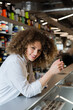 © LIGHTFIELD STUDIOS - cheerful saleswoman smiling at camera near counter in textile shop