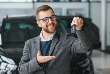 Wall Mural - Good looking, cheerful and friendly salesman poses in a car salon or showroom.