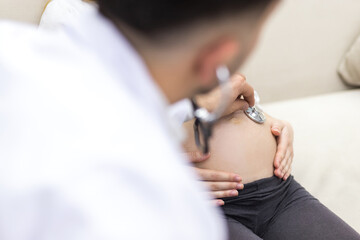 Cropped photo of doctor with stethoscope going to exam the pregnant woman.