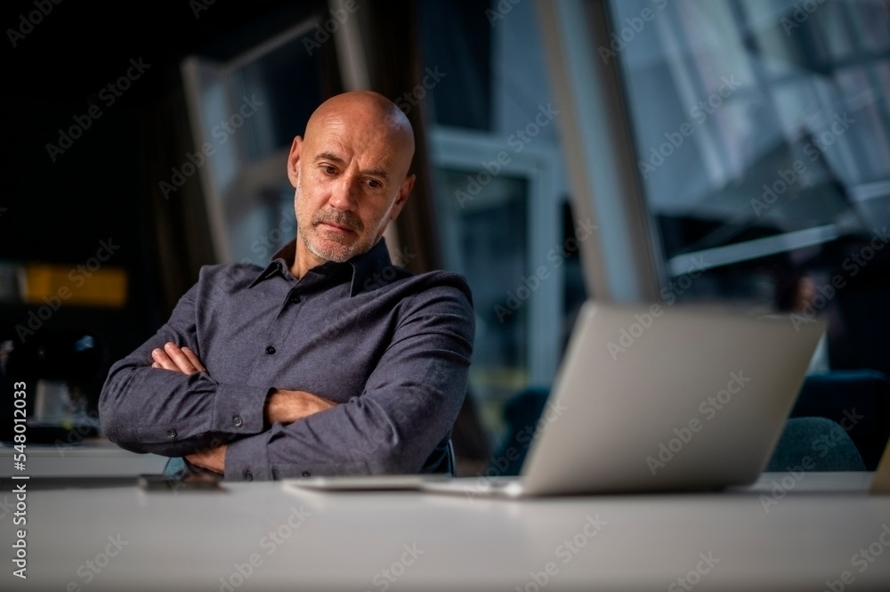 Shot of thinking business man using laptop while sitting at desk and ...