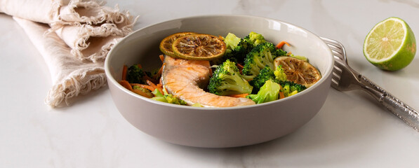 Wall Mural - a bowl of fried salmon with broccoli on a light marble table