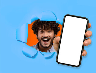 Wall Mural - Excited indian guy posing in torn, showing cell phone, mockup