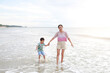 © zilvergolf - Happy Asian mom and son enjoy playing on tropical sand beach at sunrise. Happy family in summer holiday.