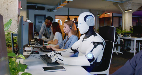 robot working at computer among people. maschine typing on keyboard in office. it team of future. fu